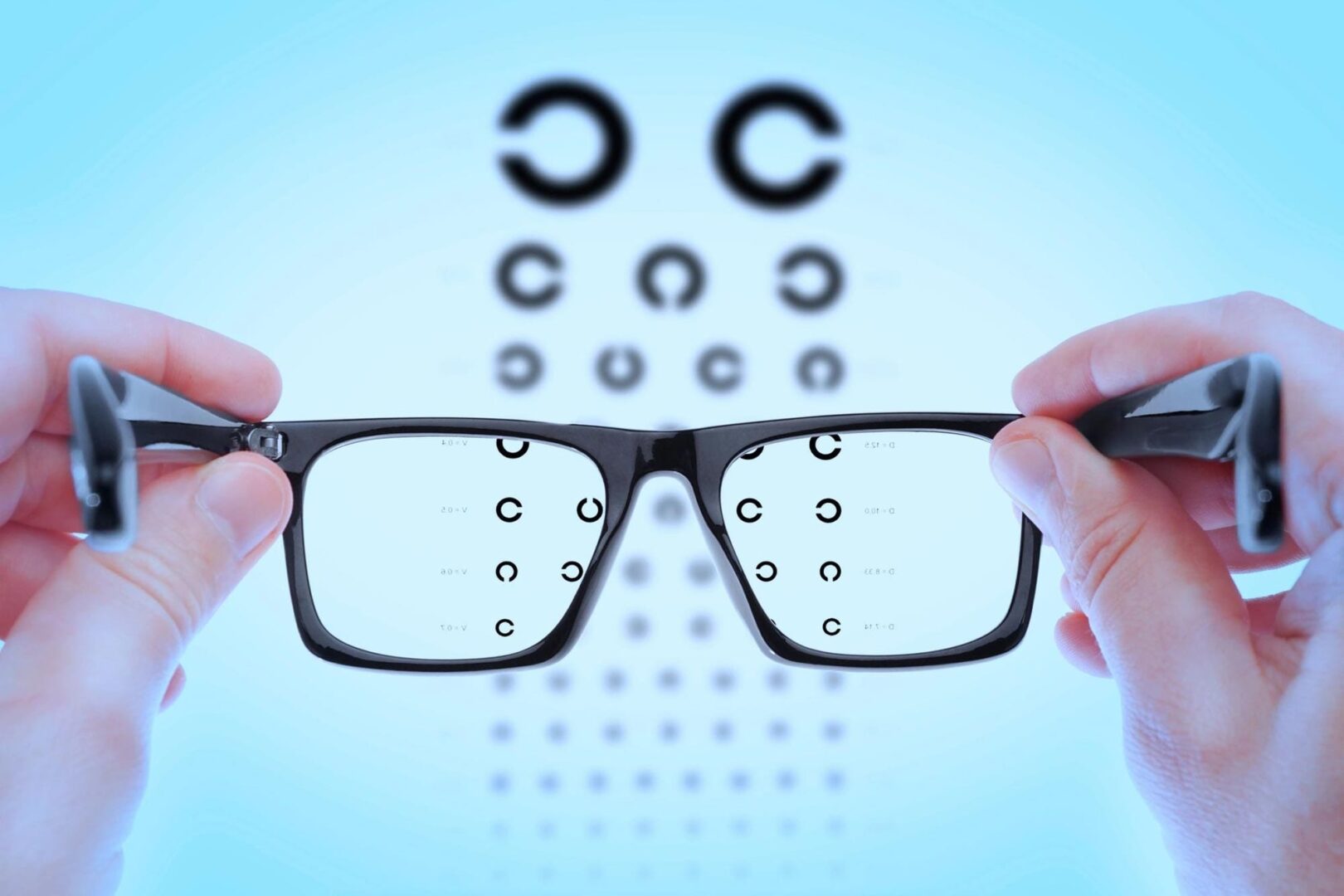 Eyeglasses held in front of vision chart.