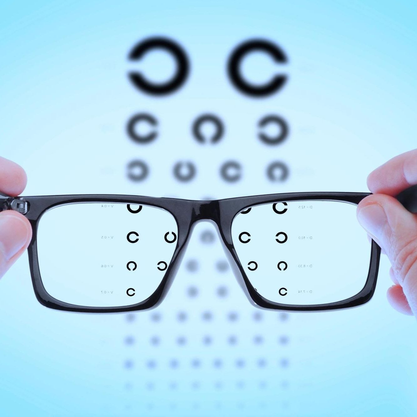 Eyeglasses held in front of vision chart.